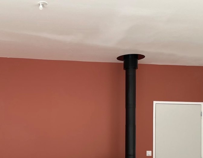 Après : salon avec un mur terracotta, un conduit de poêle et une porte